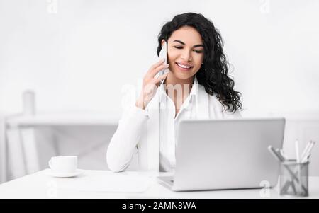 Lächelndes hispanisches Mädchen, das in der Kaffeepause telefoniert Stockfoto