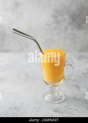 Gelbe mango Joghurt oder Smoothie auf grauem Zement Hintergrund mit Kopie Raum gelassen. Gelbwurz Lassie oder Lassi in Glas mit Metall Strohhalme Stockfoto