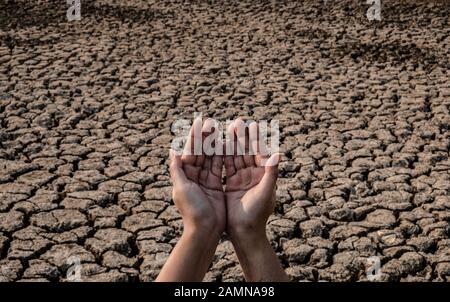 Lady Hand wartet auf Regenwasser, Gerissenen und trockenen Boden in ariden Gebieten Landschaft, Dürrekrisenkonzept Stockfoto