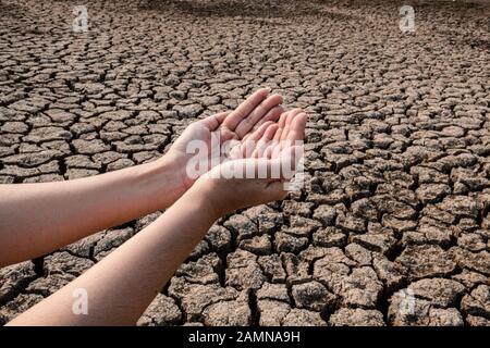 Lady Hand wartet auf Regenwasser, Gerissenen und trockenen Boden in ariden Gebieten Landschaft, Dürrekrisenkonzept Stockfoto