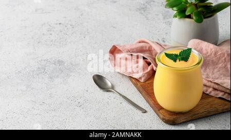 Gelbe Mango Lassi auf grauem Hintergrund. Indische mango Joghurt Drink mit Kopie Raum gelassen. Stockfoto