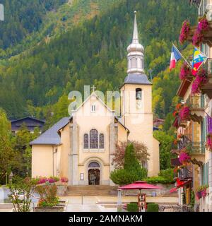 Chamonix Mont Blanc, Frankreich, Blick auf die Straße mit der katholischen Kirche von St. Michel im Herbst, Blumen und Häuser in der Stadt Stockfoto