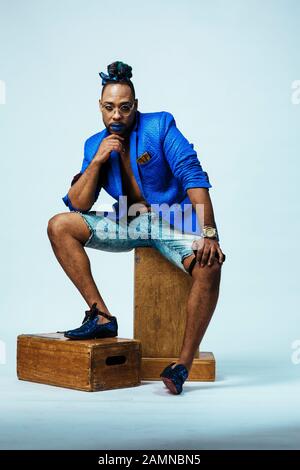 Gentleman mit blauen Lippen, die in Blau auf einem apfelkasten sitzen. Studio Foto aufnehmen Portrait Stockfoto