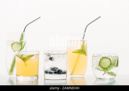 Erfrischende Getränke mit Blaubeeren, Sellerie, Strohhalmen, Minze, Gurke und Eis, isoliert auf Weiß Stockfoto