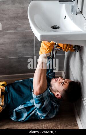 Selektive Fokussierung des Handarbeiters zur Beseitigung von Wasserschäden im Bad Stockfoto