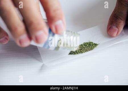 3/4-Ansicht des Mannes im T-Shirt, der medizinisches Cannabis ausgießt Stockfoto