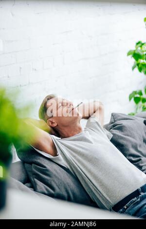 Selektive Fokussierung des gutaussehenden Mannes, der mit medizinischem Cannabis in der Wohnung stumpf raucht Stockfoto