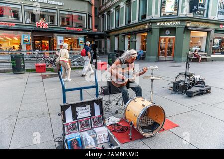 Oslo, Norway-1. August 2013: Ein Straßenmusiker tritt auf der Hauptstraße von Karl Johans Tor auf. Ein älterer Mann mit langen weißen Haaren verdient Geld auf Th Stockfoto