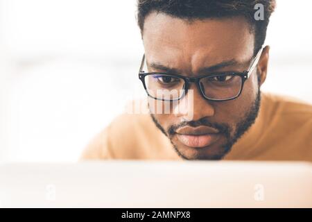 Kopfschuss des afro-Mannes, der an einem Laptop arbeitet Stockfoto