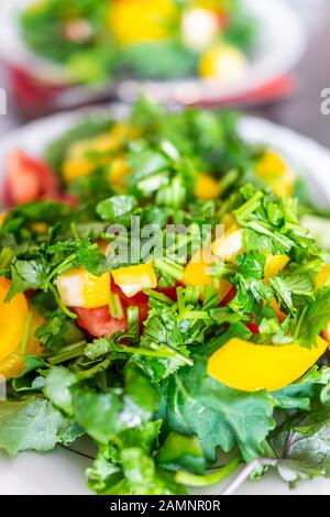 Makro-Nahaufnahme von zwei frischen Salaten auf Tellern mit Baby-Kale-Grüns, gelben Paprika und gehacktem Cilantro Stockfoto