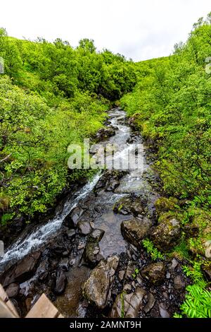 Weiter Blick auf den Fluss in der Nähe des Wasserfalls von Hunafoss hoch oben im Nationalpark Skaftafell, Island mit Wasserfelsen im üppig grünen Sommer Stockfoto