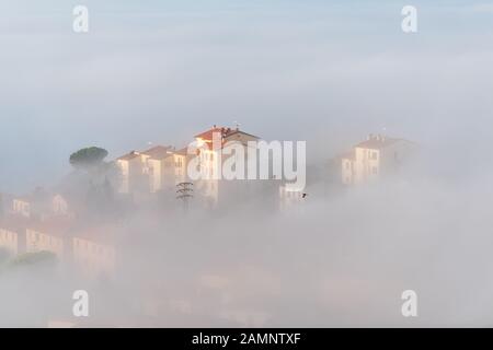 Chiusi Scalo Fog Sunrise auf dem Dach befinden sich Gebäude in Italien, Toskana mit weichen Wolken, die das Dach der Stadt überdecken Stockfoto