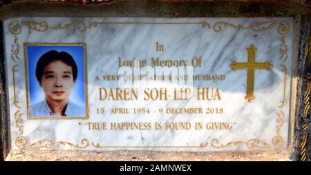 Ein "In Loving Memory"-Schild auf einem Mann's Grab außerhalb einer christlichen Kirche in Bangkok, Thailand, Asien, sagt: "Das wahre Glück gefunden im Geben' ist. Stockfoto
