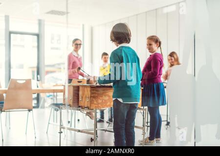 Musiklehrer mit Klassenschülern am Xylophon Stockfoto