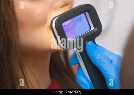 Junge Patientin wählt bei der Zahnarztbestellung die Farbe des Zahns, der Krone, des Furnieres. Zahnfarbführung. Stockfoto