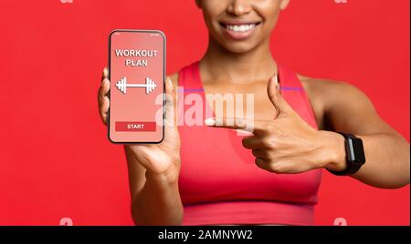 Fitness-Dame, die auf die Trainingsanwendung auf dem Telefonbildschirm zeigt Stockfoto