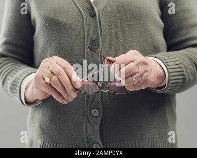 Seniorin hält Brille, Alterungskonzept, Nahaufnahme Stockfoto