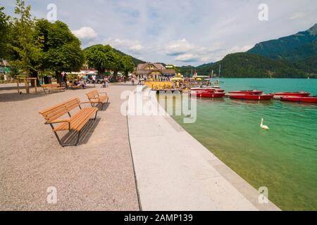 St. Gilgen, Österreich - 22. Juli 2019: Menschen, die an der Böschungspromenade am Alpensee Wolfgangsee einen warmen Sommertag genießen. Stockfoto