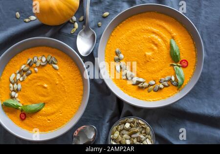 Kürbissuppe in einer Schüssel mit Basilikum, Olivenöl und Samen Stockfoto