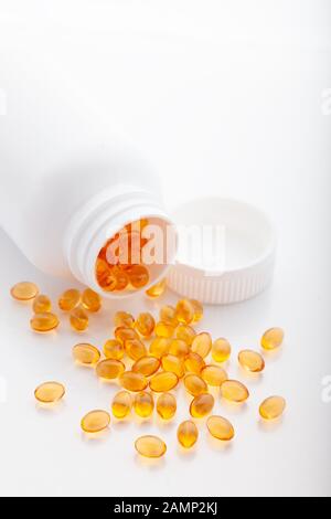 Ansicht von oben in Gold Fischöl aus pilleflasche verstreut für gute Gesundheit auf weißem Hintergrund. Zusätzliche Nahrung. Omega 3. Vitamin-E-Kapseln sa Stockfoto