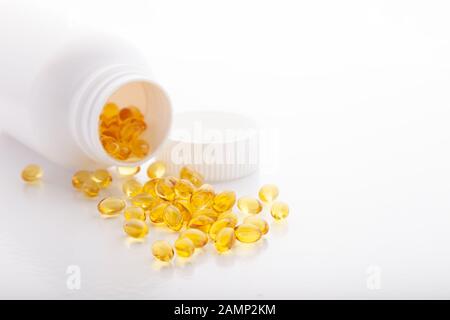 Ansicht von oben in Gold Fischöl aus pilleflasche verstreut für gute Gesundheit auf weißem Hintergrund. Zusätzliche Nahrung. Omega 3. Vitamin-E-Kapseln sa Stockfoto