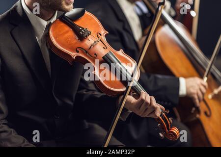 Professionelles sinfonisches Streichorchester, das auf der Bühne auftrat und ein klassisches Musikkonzert spielte, Geiger im Vordergrund Stockfoto