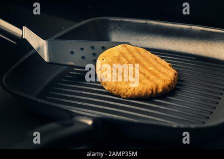 Spachtel mit veganem Burger, der auf dem Bügeleisen, vegetarischer Kost und gesundem Lifestyle-Konzept kocht Stockfoto