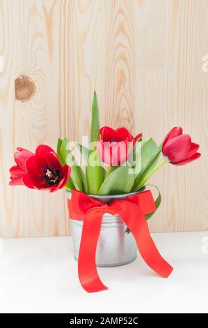 Blumenstrauß aus Tulpen in einem eisernen Eimer mit rotem Bogen Stockfoto