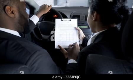 Unternehmer unterzeichnen riskanten Vertrag mit weiblicher Partnerin im Auto, Schattengeschäft Stockfoto