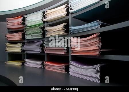 Büroregale, die mit mehrfarbigen Ordnern und Dokumenten gestapelt sind. Stockfoto