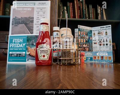 Tischeinrichtung im JD Wetherspoons Pub Yr Hen Orsaf (The Old Station) Aberystwyth, Menü-Ketchup und andere condiments Stockfoto