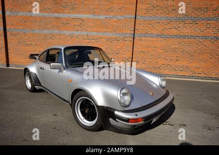 1980er Porsche 911 Turbo parkte an einem sonnigen Tag auf einem Parkplatz vor einer Mauer Stockfoto