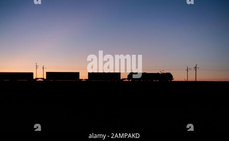 Direct Rail Services 88 bi-Modus für elektrischen und Diesellok Schleppen einer intermodalen Container Zug auf der West Coast Mainline bei Sonnenuntergang. Stockfoto