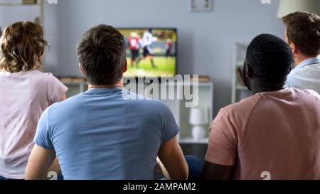 Gruppe von multiethnischen Freunden, die das Fußballteam unterstützen und das Spiel im fernsehen verfolgen Stockfoto