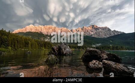 Felsen am Ufer, Eibsee vor Zugspitzmassiv mit Zugspitze, Sonnenuntergang, dramatische Mammaten-Wolken, Wetterstein Range, bei Grainau, oben Stockfoto