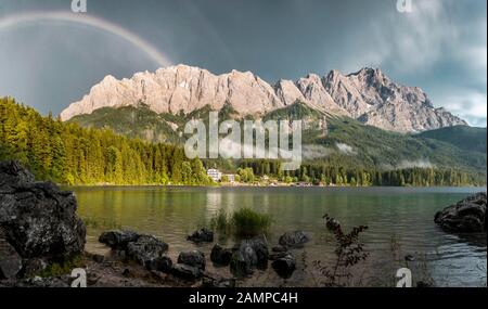 Felsen am Ufer, Eibsee vor Zugspitzmassiv mit Zugspitze mit Regenbogen, Wetterstein Range, bei Grainau, Oberbayern, Bayern Stockfoto