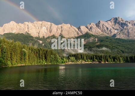 Felsen am Ufer, Eibsee vor Zugspitzmassiv mit Zugspitze mit Doppelregenbogen, Wetterstein Range, bei Grainau, Oberbayern Stockfoto