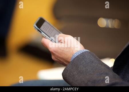 Geschäftsmann bei einer Konferenz oder einem Seminar, der auf seinem Handy im Internet surft. Stockfoto