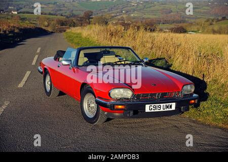 Ein rotes Jaguar XJS Cabriolet parkte an einem sonnigen Wintertag auf einer Landstraße Stockfoto