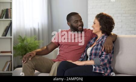 Glückliches Familienpaar sitzt auf dem Sofa und genießt Zeit zusammen, Beziehungsharmonie Stockfoto