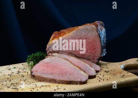 Nahaufnahme einer gemeinsamen von saftigen Roastbeef in Scheiben geschnitten auf einer hölzernen Platte. Stockfoto