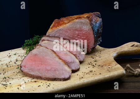 Nahaufnahme einer gemeinsamen von saftigen Roastbeef in Scheiben geschnitten auf einer hölzernen Platte. Stockfoto