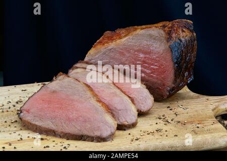 Nahaufnahme einer gemeinsamen von saftigen Roastbeef in Scheiben geschnitten auf einer hölzernen Platte. Stockfoto