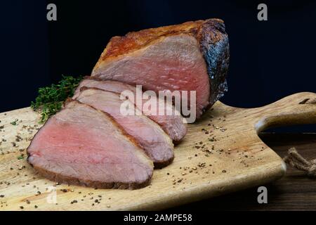 Nahaufnahme einer gemeinsamen von saftigen Roastbeef in Scheiben geschnitten auf einer hölzernen Platte. Stockfoto