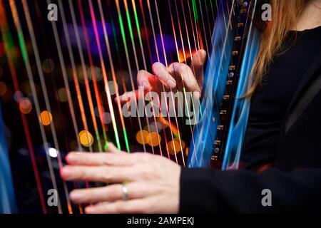 Nahaufnahme einer Frau spielt eine Harfe mit bunten Faseroptische Beleuchtung in den Streichern eingebettet. Stockfoto