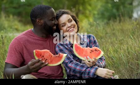 Schwarz-Weiß-Paar genießt sich selbst und isst köstliche Wassermelonen Stockfoto