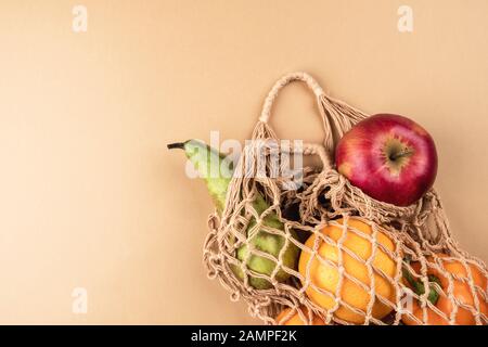 Frisches Obst und Gemüse in einer kickerfreundlichen Tasche auf beigefarbenem Hintergrund. Stockfoto