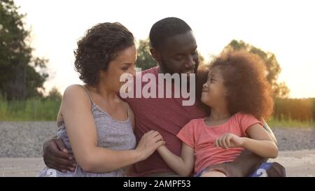 Kleines Mädchen, das Eltern mit Liebe betrachtet, harmonische Familie glücklich zusammen Stockfoto