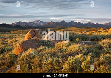 WY03958-00...WYOMING - Die untergehende Sonne, die warmes Licht über offenen Präriegebieten wirft, und der Wind River Reichen vom Hochland über dem Big Sandy Stockfoto