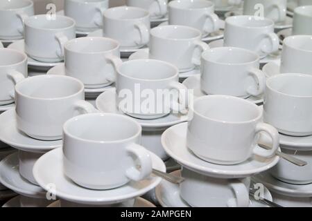 Reihen gestapelte Tassen und Untertassen betriebsbereit. Stockfoto